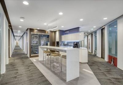 Modern breakout kitchen and bar area with sleek white finishes and stools.