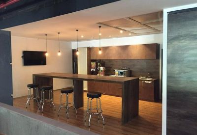Breakout area with a long wooden bar table and industrial pendant lighting.