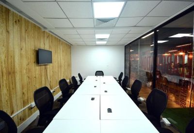 Spacious boardroom with a long white conference table and wood-paneled walls.