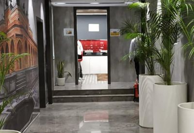Bright hallway with polished marble floors, large potted plants, and a colorful wall mural.