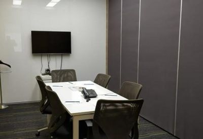 Professional four-person meeting room with a white table, wall-mounted screen, and acoustic wall panels.