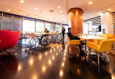 Bright communal lounge and cafe area with vibrant red and yellow seating.