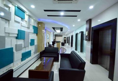 Sleek lobby area with black leather sofas, blue accent wall panels, and a polished floor.