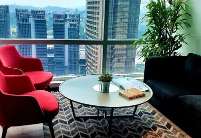 Lounge area with red armchairs, a geometric rug, and a large window overlooking the city skyline.