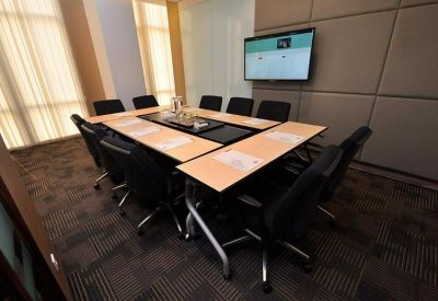 Modern meeting room with a central U-shaped table and wall-mounted monitor.