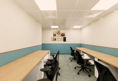 Workspace with facing desks and teal wall panels under bright square lighting.