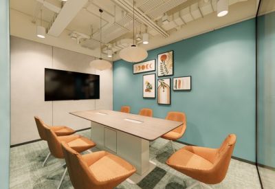 Modern meeting room with orange chairs, a teal feature wall, and a large wall-mounted screen.