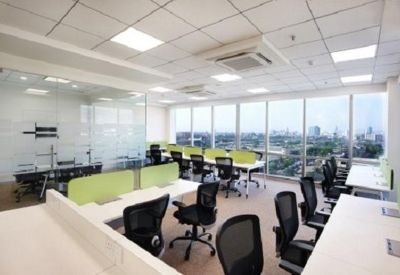Large office area with rows of workstations and floor-to-ceiling windows showing city views.