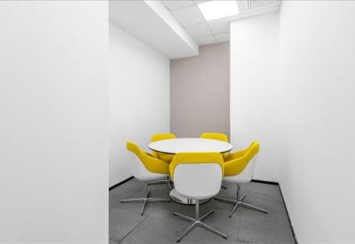Small breakout room with a round white table and four yellow chairs.