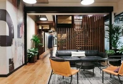 Lounge area with leather sofa, orange chairs, and a bold abstract mural at The Galaxy Hotel.
