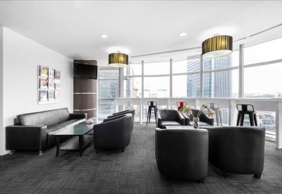 Stylish lounge area with dark grey armchairs, a leather sofa, and expansive window views.