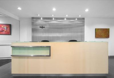 Modern minimalist reception desk with light wood paneling and sleek silver accents.