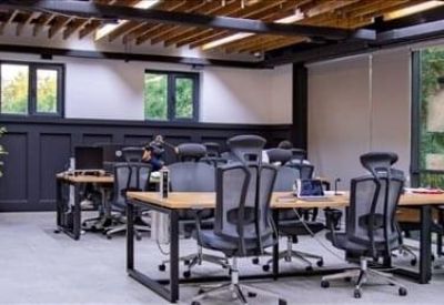Bright private office suite with two desks, ergonomic chairs, and a vibrant lime green feature wall.