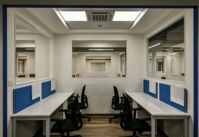 Small internal office suite with two rows of desks separated by blue privacy partitions.