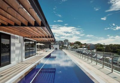 Rooftop swimming pool with city views under a wooden pergola structure.