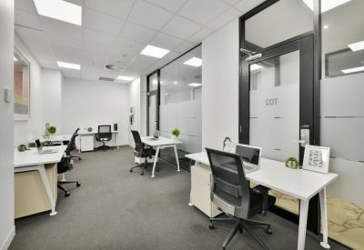 Modern meeting room with a wooden table, black leather chairs, and a large wall-mounted screen.