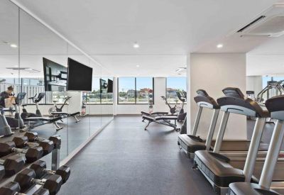 In-house fitness center featuring treadmills, dumbbells, and wall-mounted televisions.