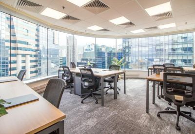 Well-lit shared office space with multiple desks and city views.