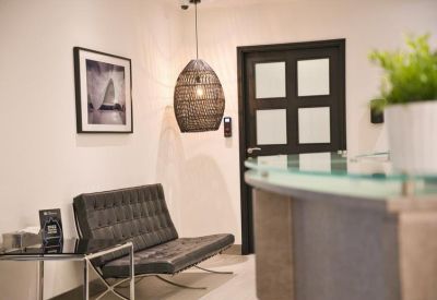 Modern lounge area with a black leather sofa and contemporary woven pendant light.