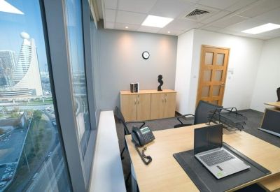 Bright private office suite featuring a wooden desk, laptop, and large window.