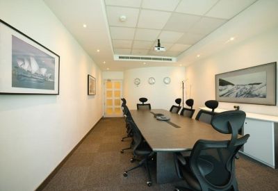 Professional boardroom with a long dark wood table and ergonomic black chairs.