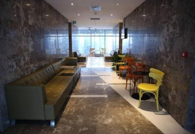 Modern hallway lounge with olive green leather sofas and yellow accent chair.