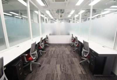 Sleek office hallway with glass-walled private suites and grey carpet.
