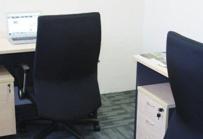 Brightly lit workspace with two black ergonomic chairs and white desks with integrated storage.