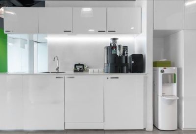 Modern white kitchenette area with coffee machines and a water dispenser.