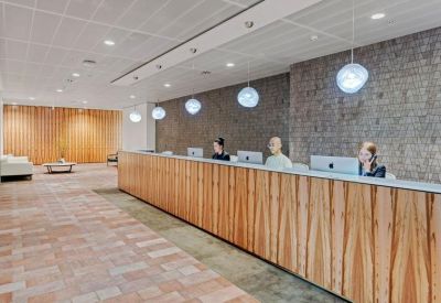 Sleek wooden reception desk backed by a textured stone wall and designer pendant lighting.