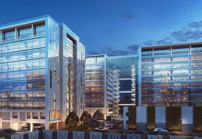 Wide courtyard view between several contemporary office buildings with glass walls and lit interiors.