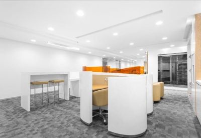 Modern communal breakout area with curved white privacy booths and a high-top table.