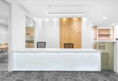 Bright reception area featuring a white backlit front desk and wood-paneled walls.