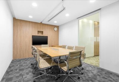 Professional boardroom featuring a large light wood table and ergonomic mesh chairs.