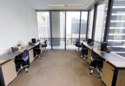 Open-plan workspace with six desks facing floor-to-ceiling windows with city views.