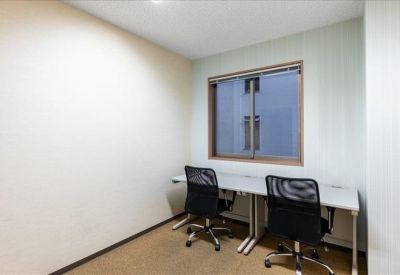 Compact two-person office with a window and white walls.