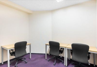 Bright internal office suite with three white desks and black ergonomic chairs.