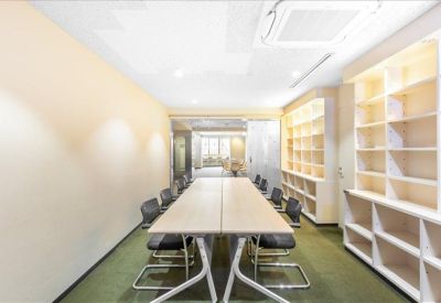 Long meeting room with a wooden table, black chairs, and floor-to-ceiling white shelving.
