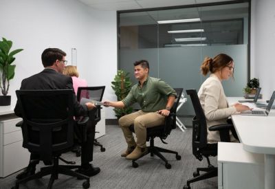 Bright open-plan office suite with people working at desks and indoor plants.