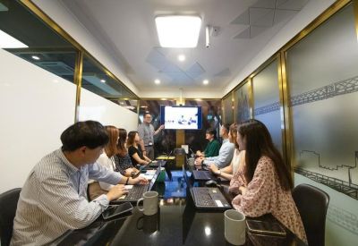 Meeting room with a team gathered around a dark table for a digital presentation.