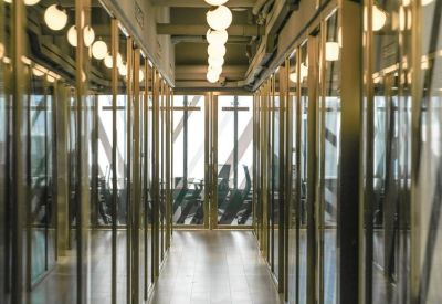 Polished corridor featuring glass walls and overhead globe lighting.