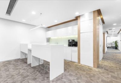 White communal kitchen and break area with bar-height seating and wood accents.