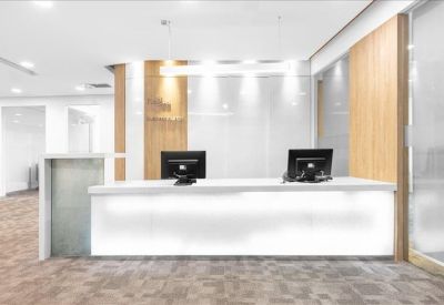 Sleek white reception desk with two monitors and warm wood wall accents.