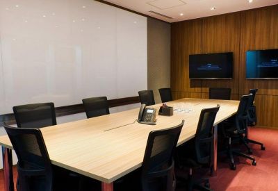 Professional boardroom featuring a long wooden table, black ergonomic chairs, and a whiteboard.