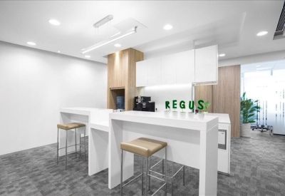 Communal breakout area featuring white high-top tables and tan stools.