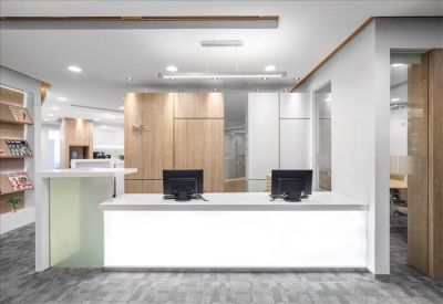 Bright reception area with a minimalist white front desk and wooden wall accents.