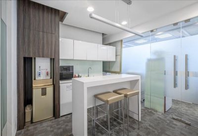 Modern office kitchenette with a white breakfast bar and high stools.