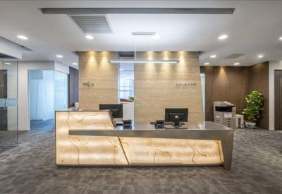 Sleek reception area with a backlit stone desk and wood-paneled walls.