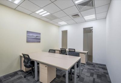 Bright office space featuring two long desks and grid ceiling lights.