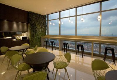 Bright communal lounge with cafe seating, bar stools, and a lush vertical garden wall.